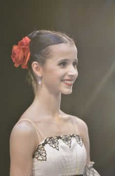 a woman with a flower in her hair smiles at the camera while wearing a white and black dress