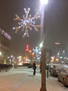 a snow covered street with cars parked on the side and people walking down the sidewalk