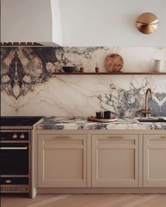 a kitchen with marble counter tops and gold accents on the wall, along with wooden floors