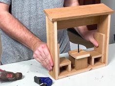 a man is making a wooden toy house