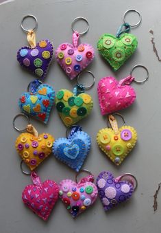 many different colored heart shaped key chains on a table with holes in the middle and buttons attached to them