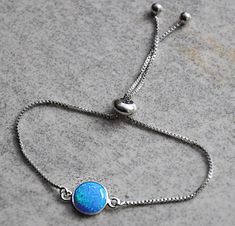 "Shop Blue Opal Bracelet, Bolo Bracelet For Women, October Birthstone, Bridal Jewelry October birthstone opal bracelet for women will make a great gift! Your order will arrive nicely packaged ready to be given. The opal bracelet is made from: - Lab created blue opal cabochon (10mm) set in sterling silver bezel - Stainless steel box chain This bracelet is fully adjustable. The silicone-lined round bead (6mm) slides along the chain and holds its position where you place it. Total length of the bra Adjustable Opal Round Bracelets, Adjustable Round Opal Bracelets, Blue Opal Bracelets For Gift, Adjustable Opal Gemstone Bracelets, Adjustable Opal Gemstone Bracelet, Adjustable Opal Bracelet Gift, Adjustable Opal Bracelet For Gift, Silver Opal Bracelet Gift, Jewelry Opal