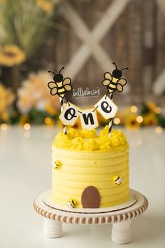 a bee themed birthday cake with yellow frosting and honeycombs on top that says one