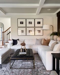 a living room filled with white furniture and pictures on the wall above it's coffee table