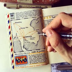 a person holding a pen and looking at an open book with stamps on it,