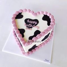 a heart shaped birthday cake with pink and black icing on it's side