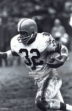 an old black and white photo of a football player running with the ball in his hand