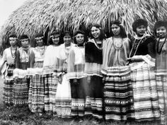 a group of women standing next to each other in front of a hut