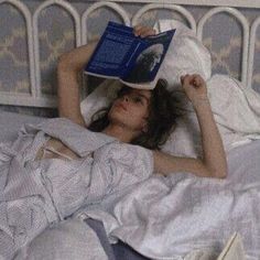 a woman laying in bed with an open book on her head