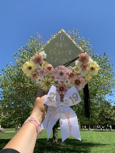 someone holding up a graduation cap with flowers on it