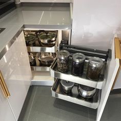 an open drawer in a kitchen with pots and pans on the bottom shelf next to it