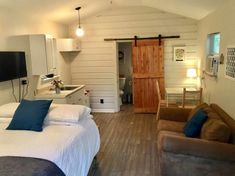 a bed room with two beds and a tv on a stand next to a kitchen