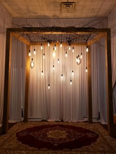 a room with curtains and lights hanging from it's ceiling, along with a rug on the floor