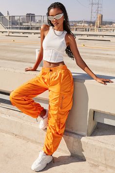 It’s giving off-duty vibes! Our Women's High-Rise Rouched Nylon Jogger is the perfect baggy pant to add to your wardrobe! Designed with an adjustable bungee cord at the elasticized waistband for the perfect fit and comfort. These high waisted pants are meant to be oversized with a baggy and slouchy fit. Featuring silver hardware and large cargo pockets for a sporty-chic vibe. We’ve also added adjustable bungee cords at the bottom hems to give you the option of wearing them more scrunched up at t Sporty Parachute Pants For Summer Outdoor, Sporty Summer Parachute Pants For Outdoor, Casual Nylon Cargo Pants For Summer, Summer Casual Nylon Cargo Pants, Summer Streetwear Cargo Pants With Elastic Waistband, Summer Utility Parachute Pants For Outdoor Activities, Urban Style Summer Cargo Pants With Elastic Waistband, Urban Cargo Pants For Summer Outdoor Activities, Urban Style Summer Cargo Pants For Outdoor Activities