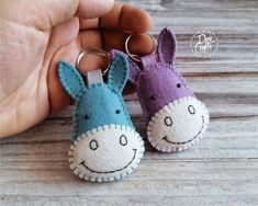 two small stuffed animals are being held by someone's hand on a wooden table