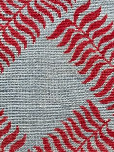 a red and white rug with leaves on the bottom, in front of a light blue background