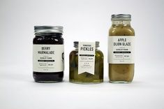 three jars filled with pickles sitting next to each other