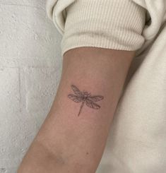 a small dragonfly tattoo on the arm