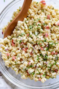 a bowl filled with macaroni salad and a wooden spoon