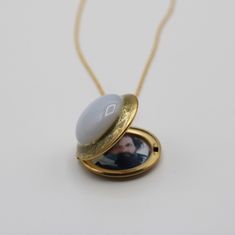 "This locket features a stunning glass moonstone surrounded by gold enamel. It opens to hold two photographs. ~Locket is stainless steel plated gold 1\" ~Gold plated brass chain ~Hand enameled" Gold Cameo Necklace For Keepsake, Gold Locket Jewelry For Memorial, Gold Memorial Locket Jewelry, Gold Spiritual Locket Necklace For Anniversary, Elegant Gold Locket Necklace For Wedding Gift, Cabochon Round Pendant Jewelry For Weddings, Gold Cameo Jewelry Gift, Gold Polished Keepsake Locket Necklace, Gold Cameo Jewelry As Gift