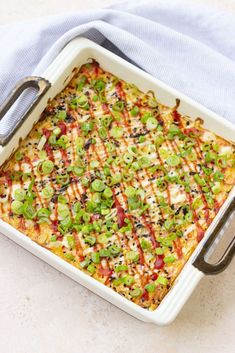 a casserole dish with vegetables and cheese in it sitting on a blue towel