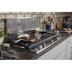 a stainless steel stove top oven sitting next to a counter with pots and pans on it