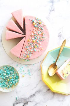 a cake with sprinkles on it next to a plate with a piece of cake