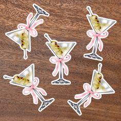 six martini glasses with pink bows on wooden table next to each other, all decorated in different shapes and sizes