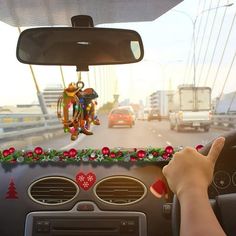 a person driving down the road with christmas decorations on their dash board and ornaments hanging from the ceiling