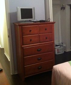 a bedroom with a bed, dresser and television on top of the dresser in it