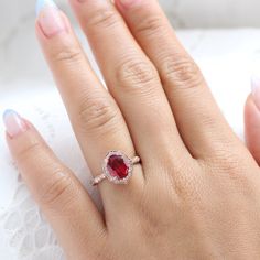 a woman's hand with a ring on it and a red stone in the middle