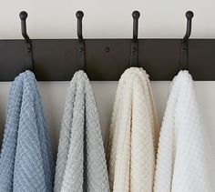 four towels hanging on a rail in a row with black handles and two white ones