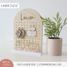 a wooden sign with earrings on it next to a potted plant and the words laser cut