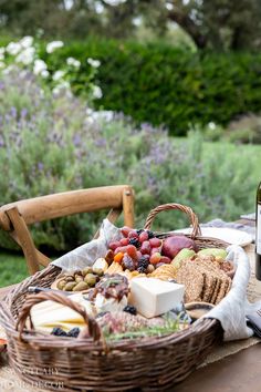 a wine bottle sitting on top of a table next to a basket filled with food