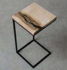 a wooden side table with metal legs and a blue bird on it's back