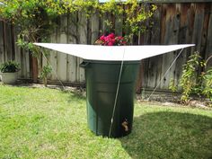 a green trash can sitting in the middle of a yard