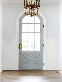 a door with a chandelier hanging from it's side in front of a white wall