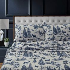 a bed covered in blue and white comforter next to a night stand