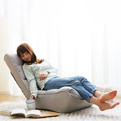 a woman laying on top of a chair next to a book