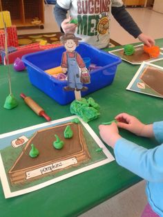 two children are playing with construction paper and plastic toys at a table in a classroom