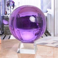 a purple glass ball sitting on top of a wooden table