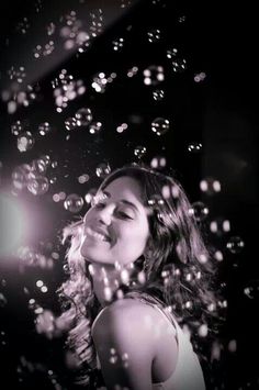 black and white photograph of a woman with bubbles in the air above her head, looking up into the sky