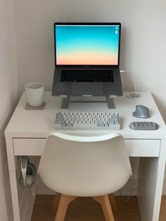 a white desk with a laptop and keyboard on it