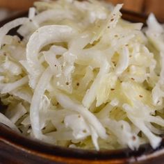 a wooden bowl filled with shredded onions on top of a table