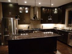 a kitchen with dark cabinets and stainless steel appliances