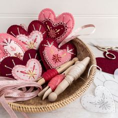 several heart shaped ornaments in a basket on a table with scissors, thread and other crafting supplies