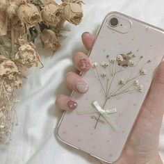 a woman's hand holding an iphone case with flowers on it