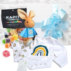 a baby gift hamper with a teddy bear, shirt and gummy bears