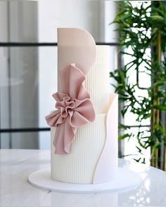 a three tiered cake with pink bows on it's side and white icing