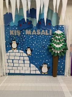 a bulletin board with penguins on it and a christmas tree in the middle, surrounded by snow